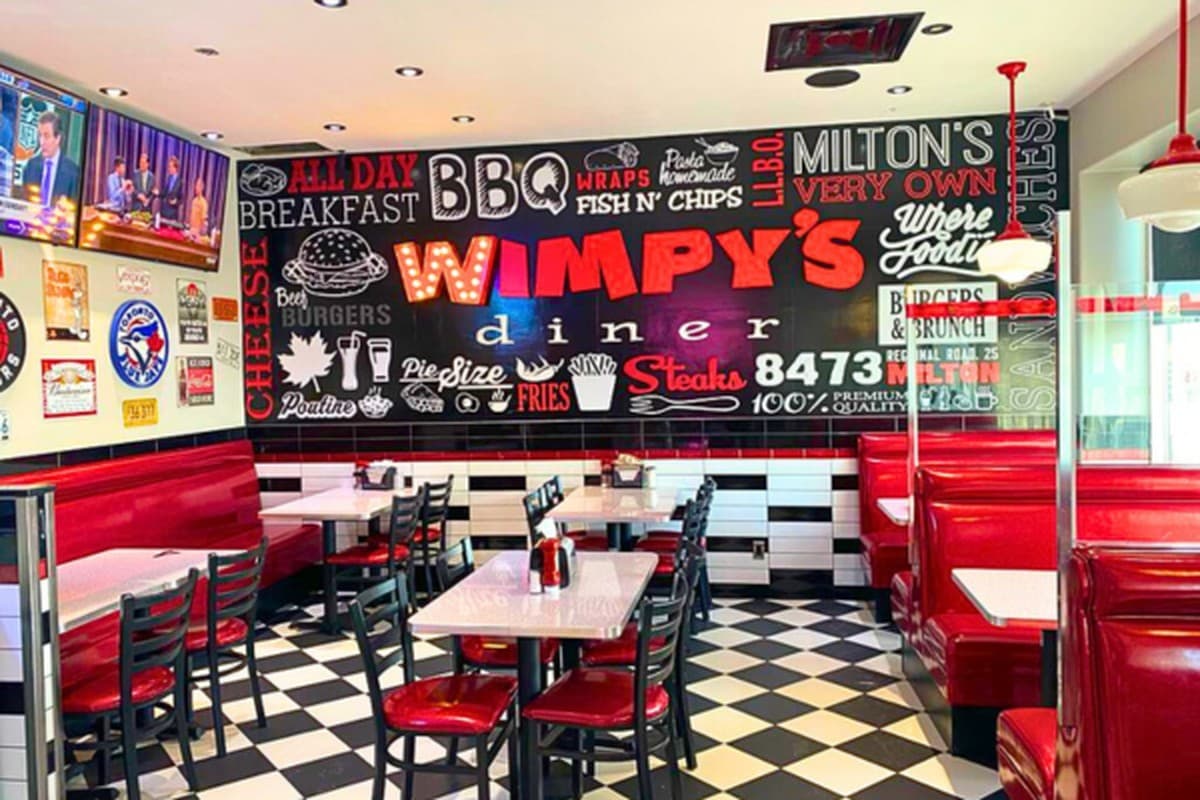 Inside a Wimpy's Diner with red vinyl booths, a black and white checkerboard floor and retro neon signage
